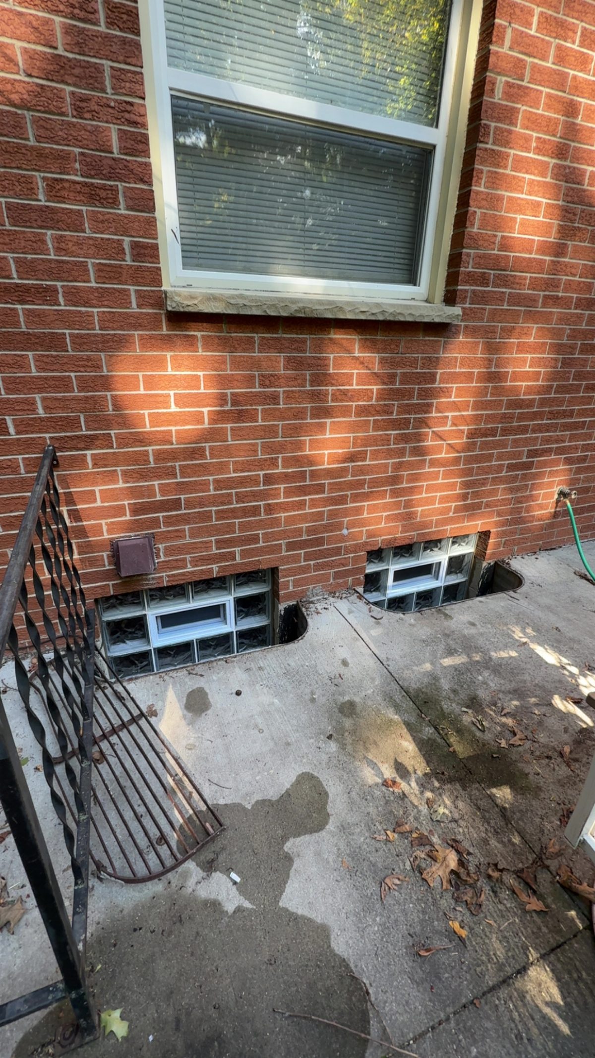 Two new vented glass block basement windows in a brick home, exterior view.