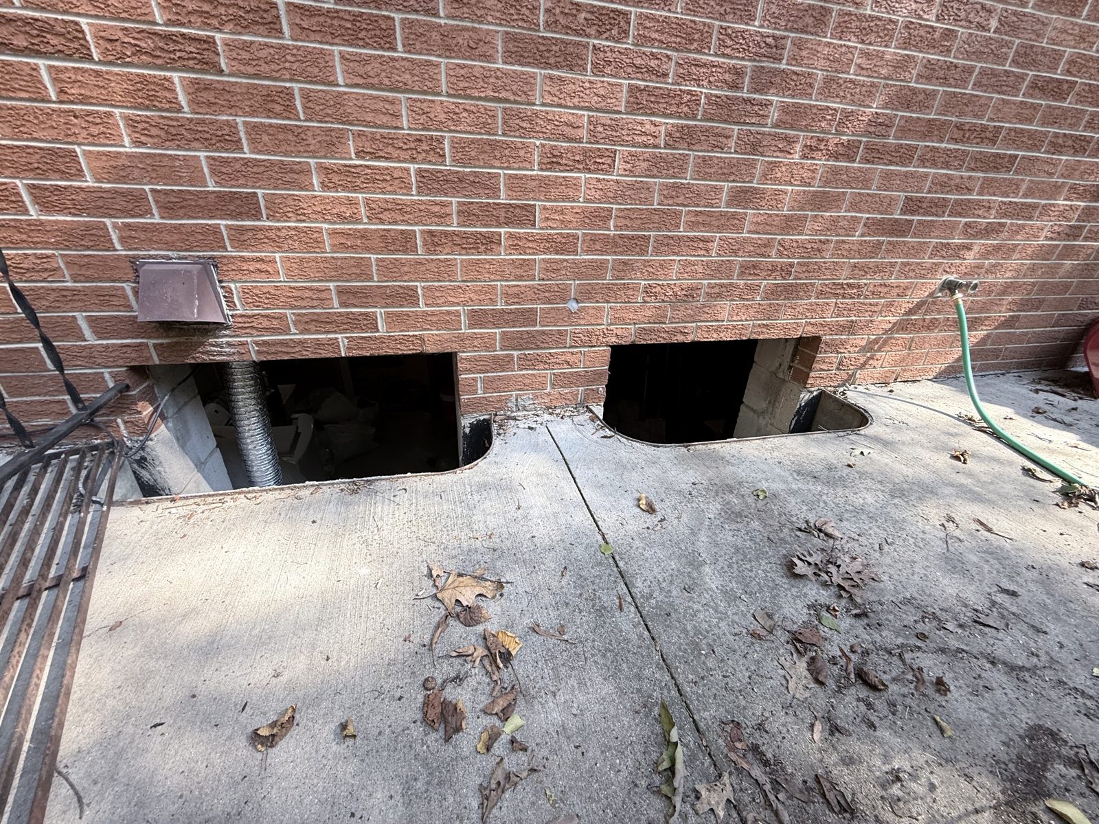 Old basement windows removed from a brick foundation, openings ready for glass block.