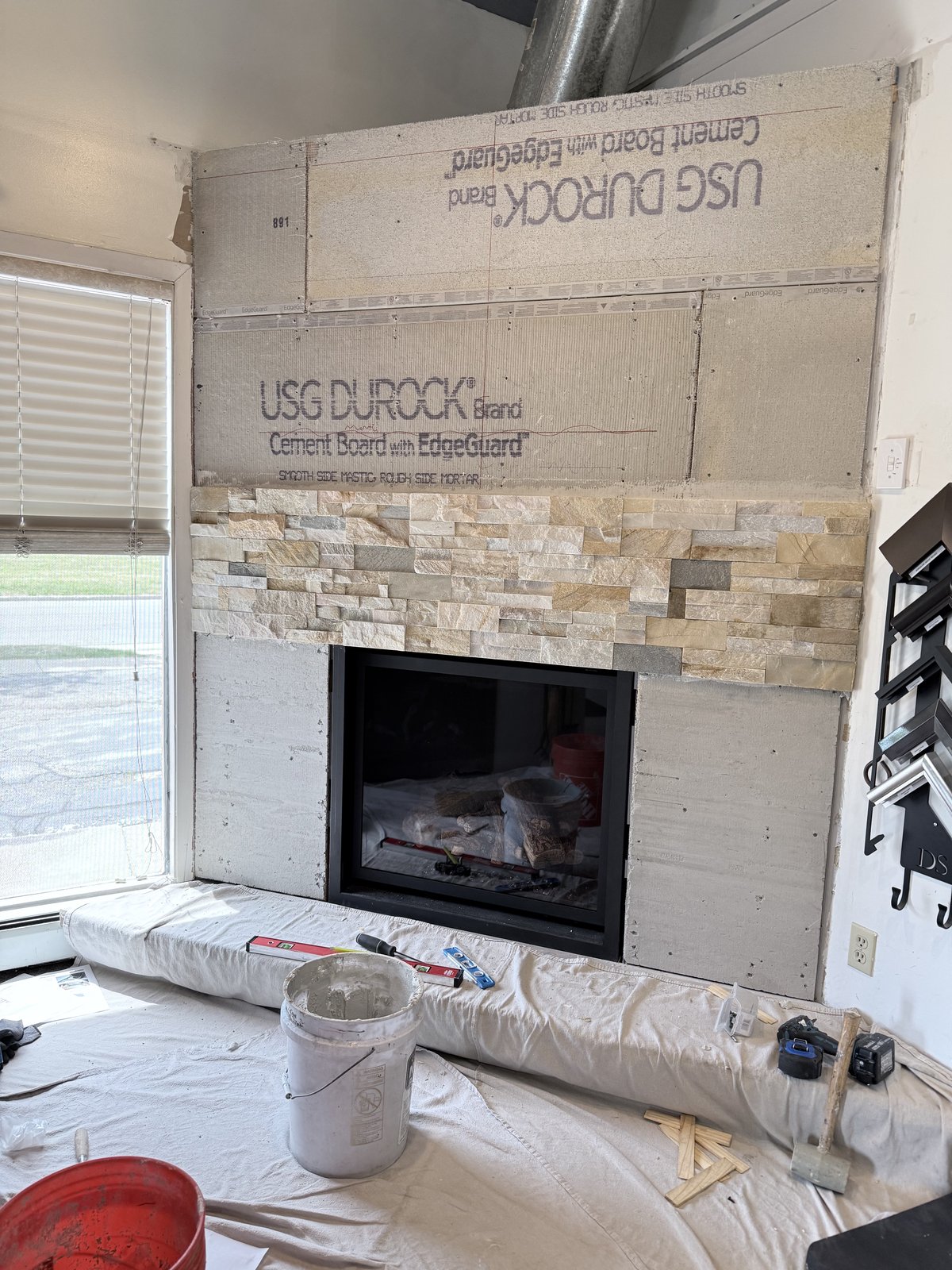 Cement-board fireplace wall with partial stacked-stone veneer install.