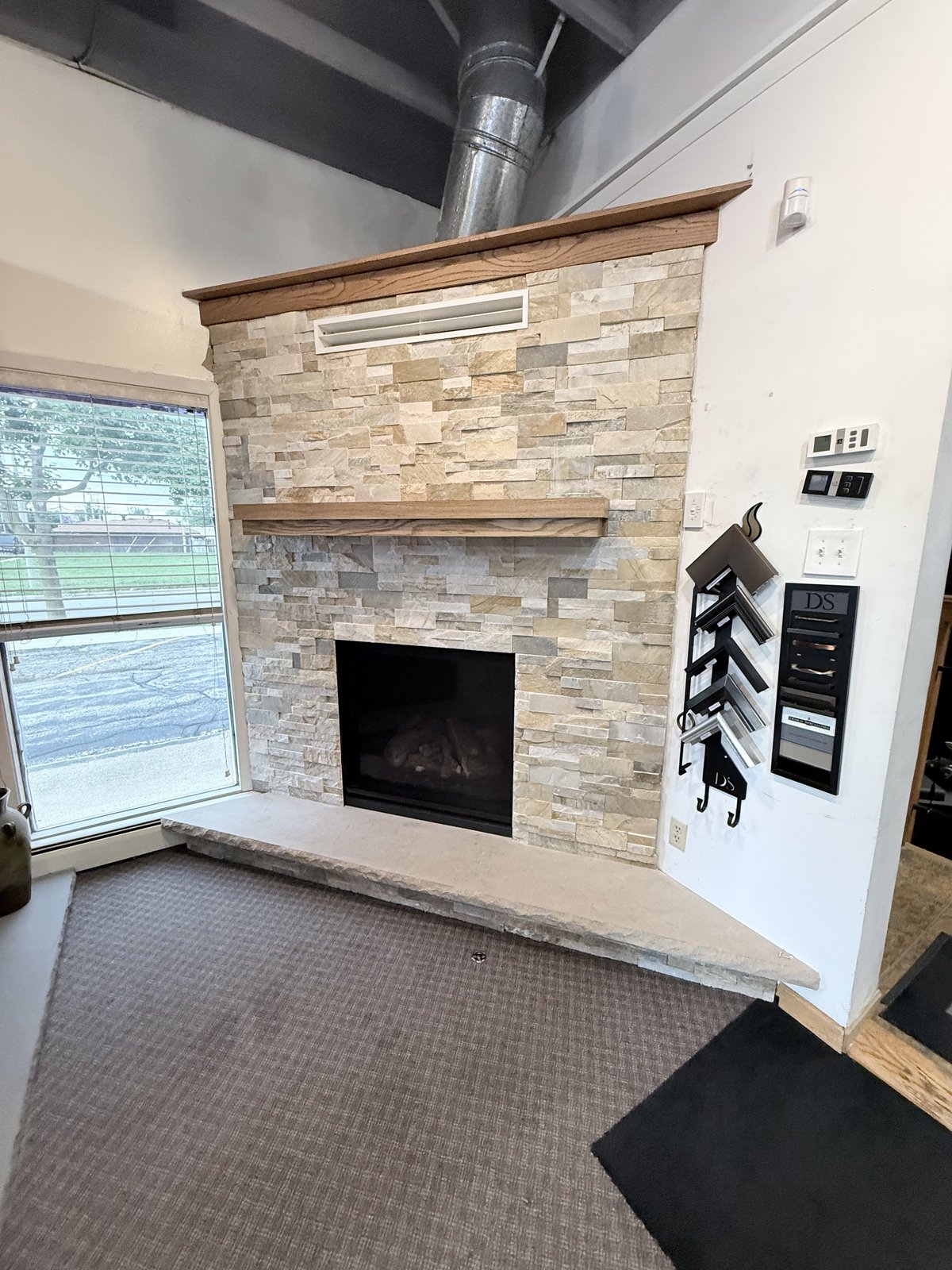 Finished stacked-stone fireplace surround with wood mantel and stone hearth.