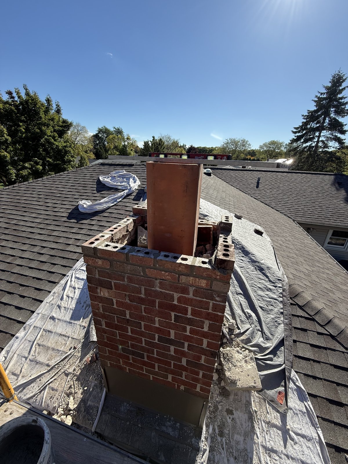 Greenfield chimney code build-up in progress with clay flue liner and level.
